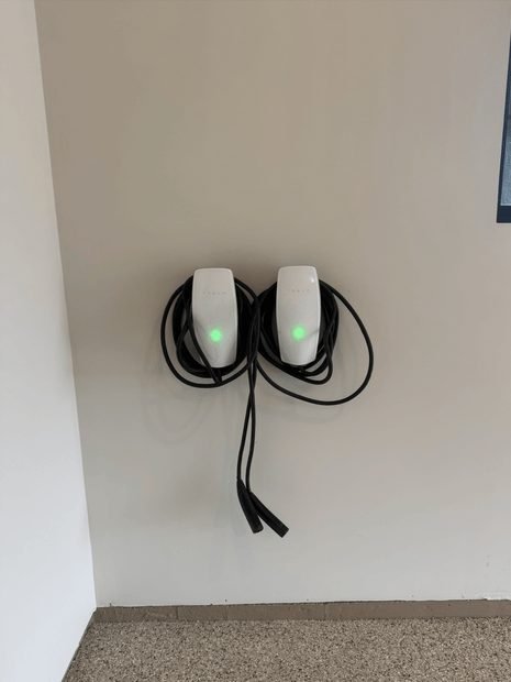 Two Level 2 EV chargers mounted side by side on a garage wall, status lights green