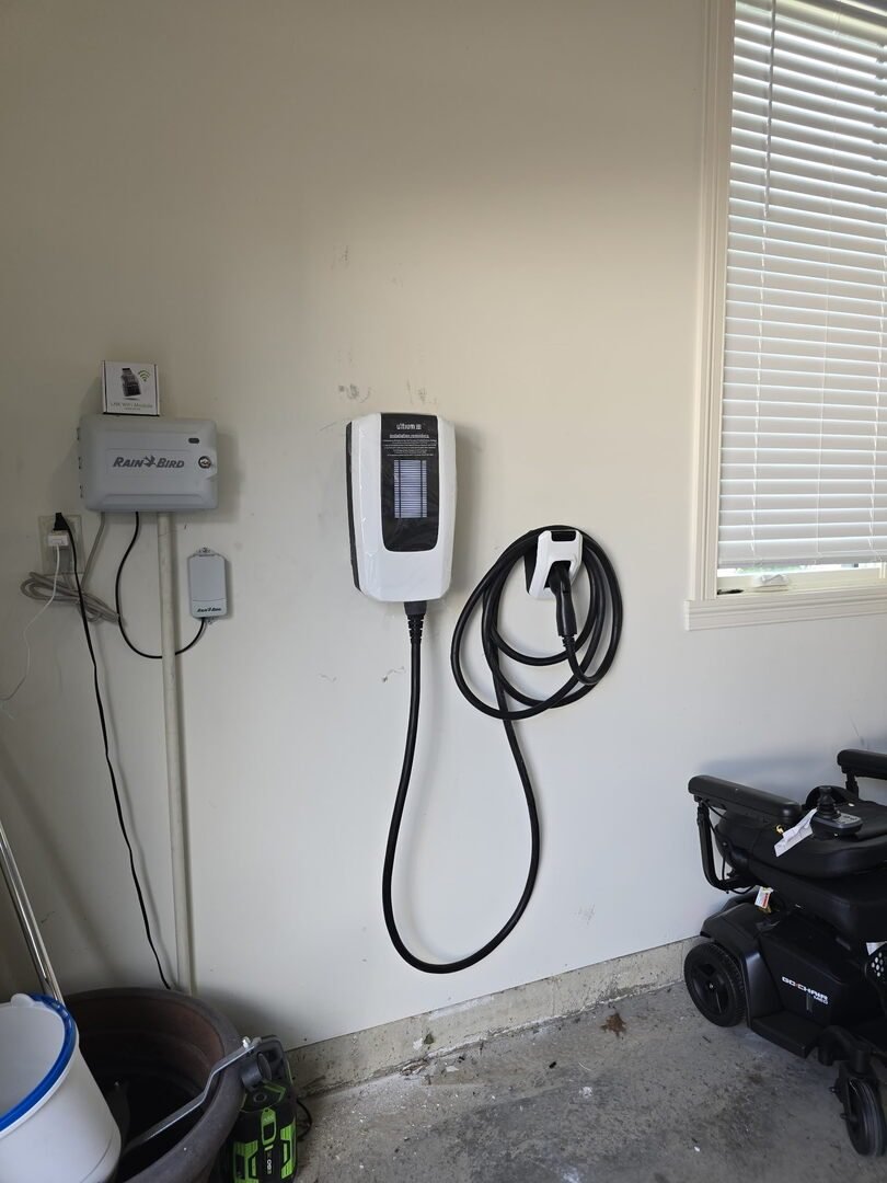 Level 2 EV charger mounted on a garage wall with its cable coiled beside a disconnect